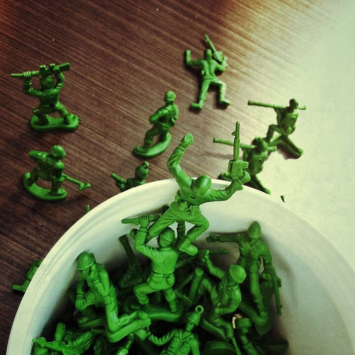 Foto de un balde lleno de soldaditos verdes de plástico.